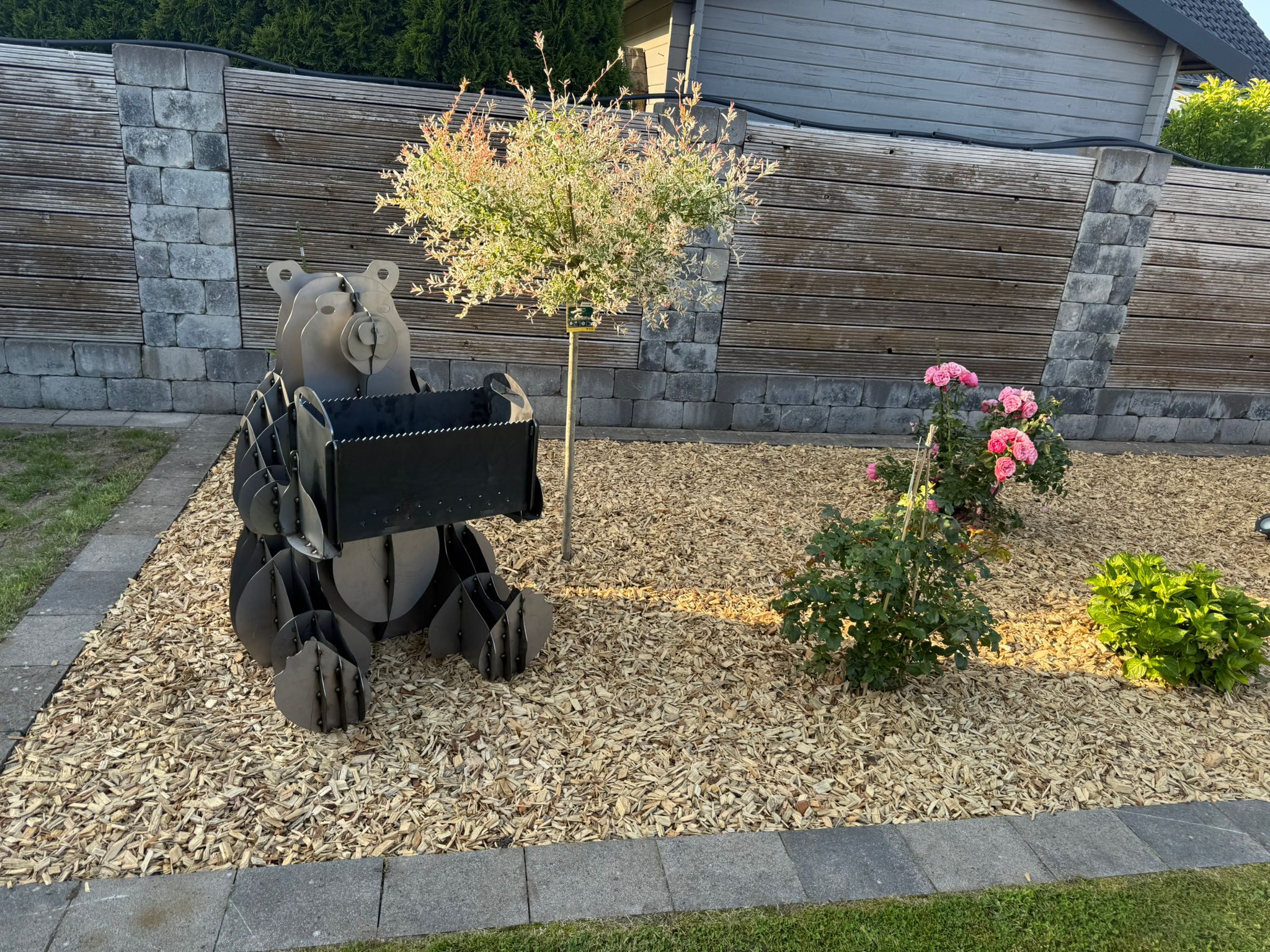 Ein Bär aus Metall, gefertigt mit einem Blumenkasten.